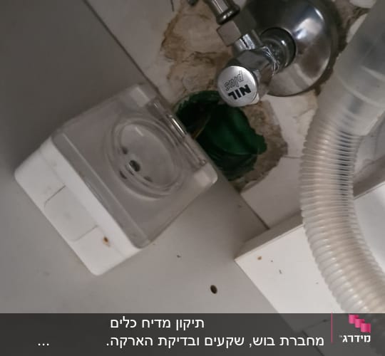 שקע חשמלי ליד צינור מתכת וגומי ירוק